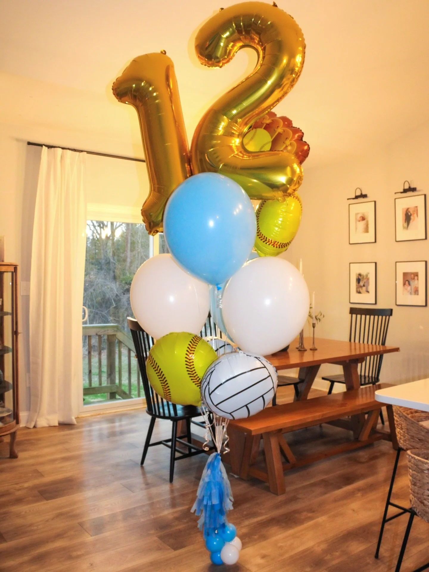 A bouquet of balloons with some shaped like baseballs and a large gold number '12' balloon.