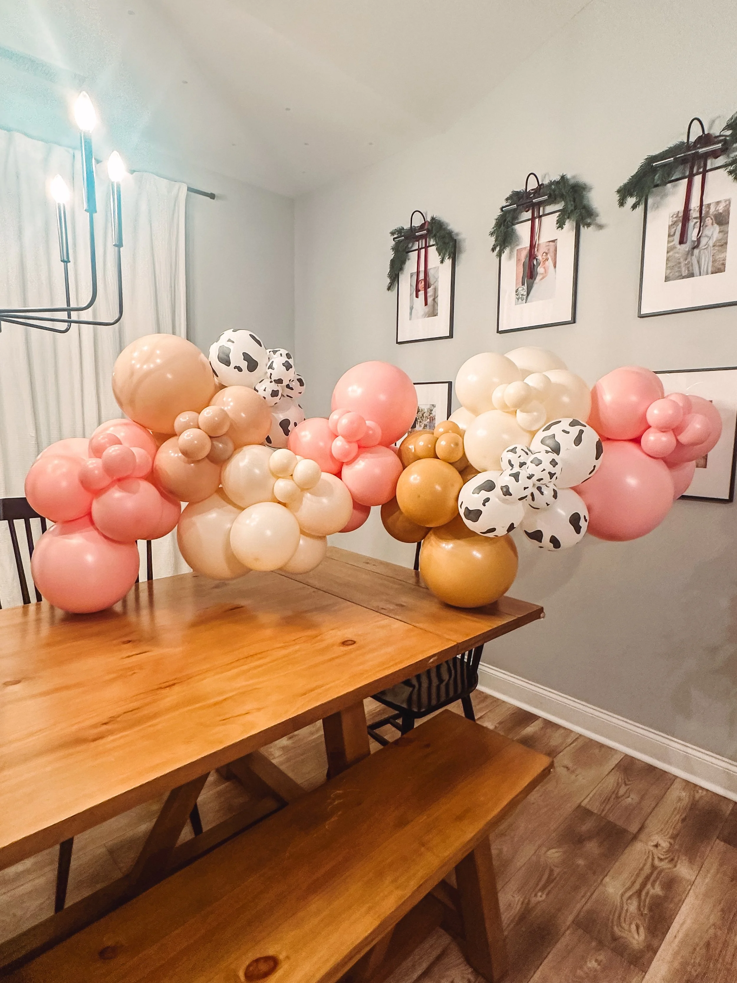Decorative balloon arrangement with pink, white, tan, and black and white cow print balloons 