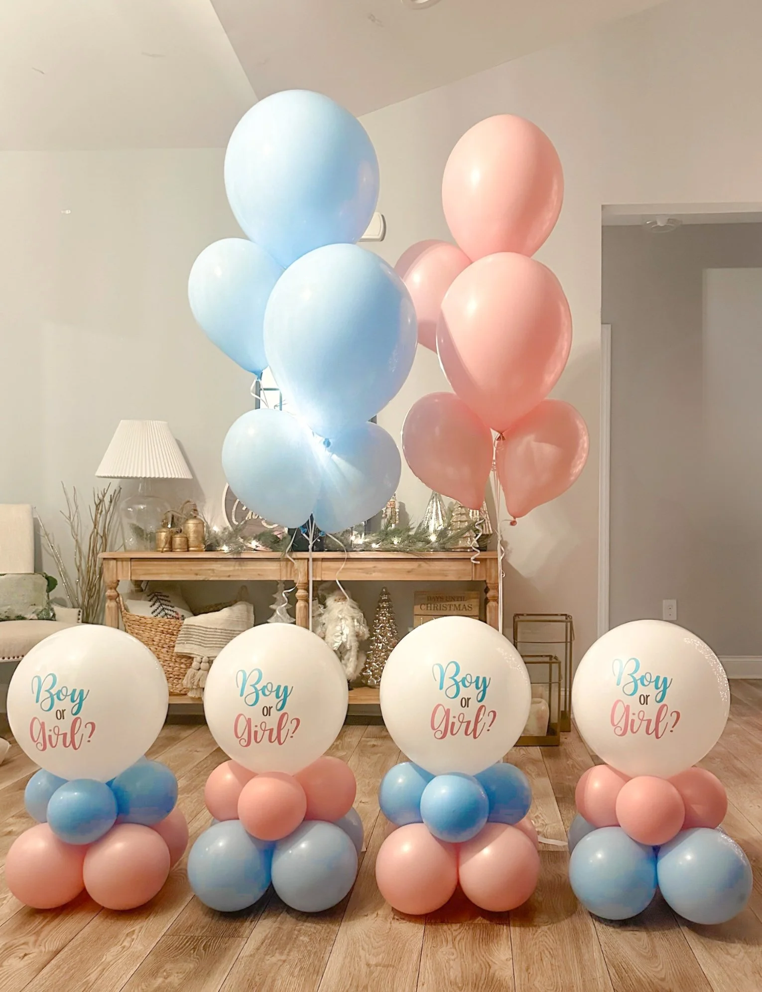Decorative balloons in pink, blue, and white, with four balloons on the floor featuring labels that say "Boy or Girl?" for a gender reveal party.