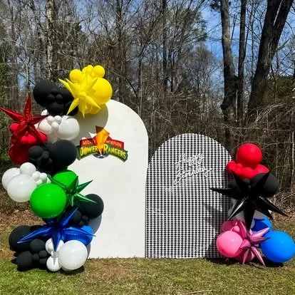 Colorful balloon decorations with Power Rangers logo in outdoor park setting.