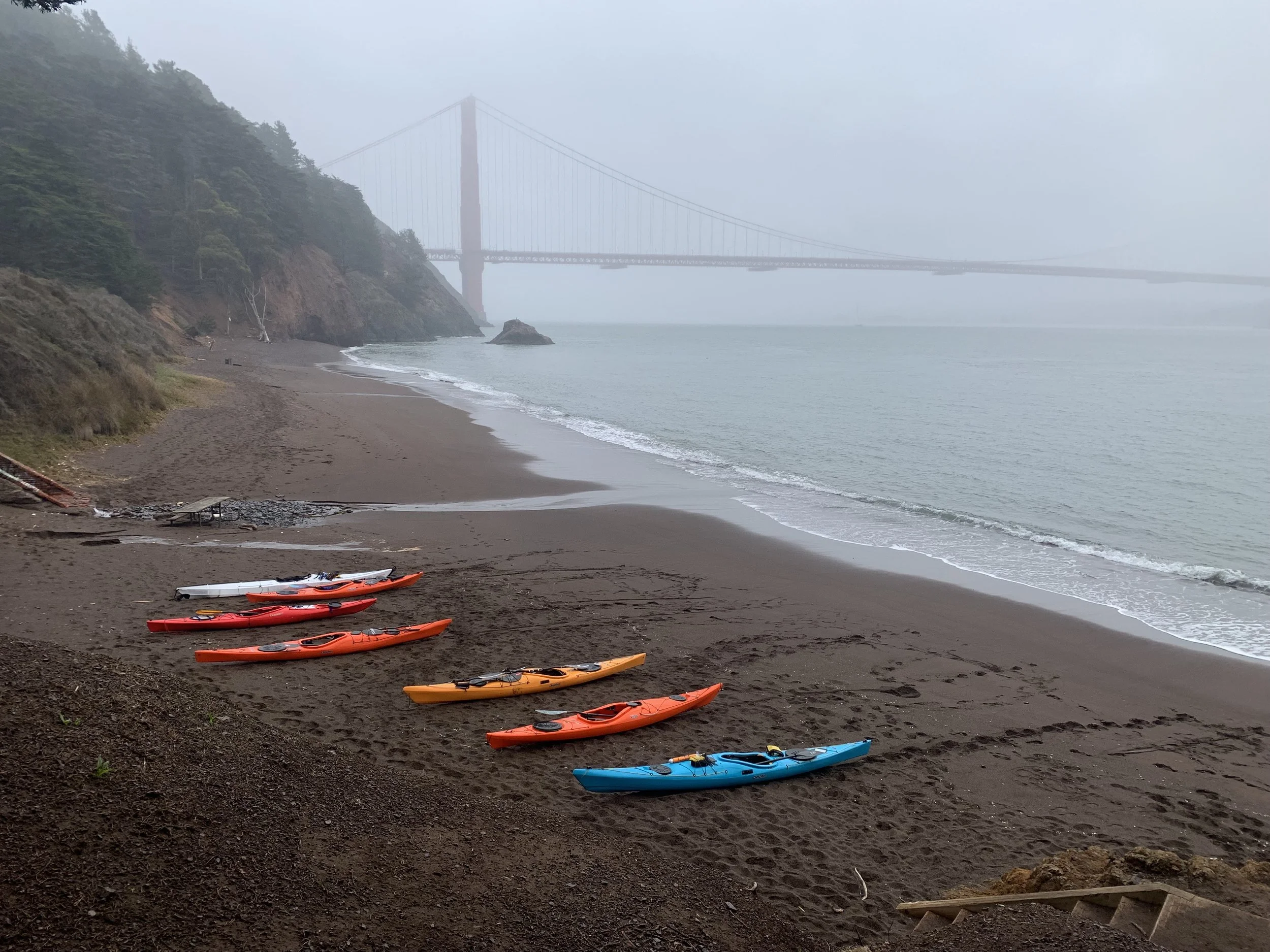 Kayaks on a foggy beach with Golden Gate Bridge in background