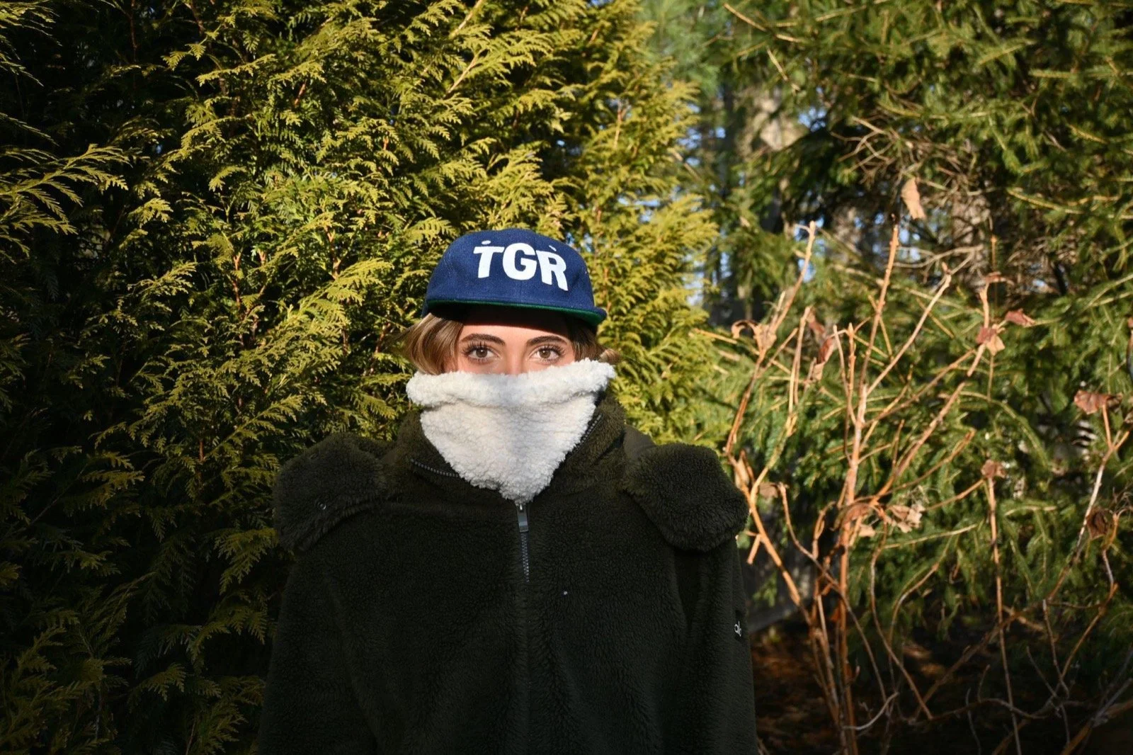 Rider in a navy cap and dark jacket wearing the Cream Sherpa neckie over their face