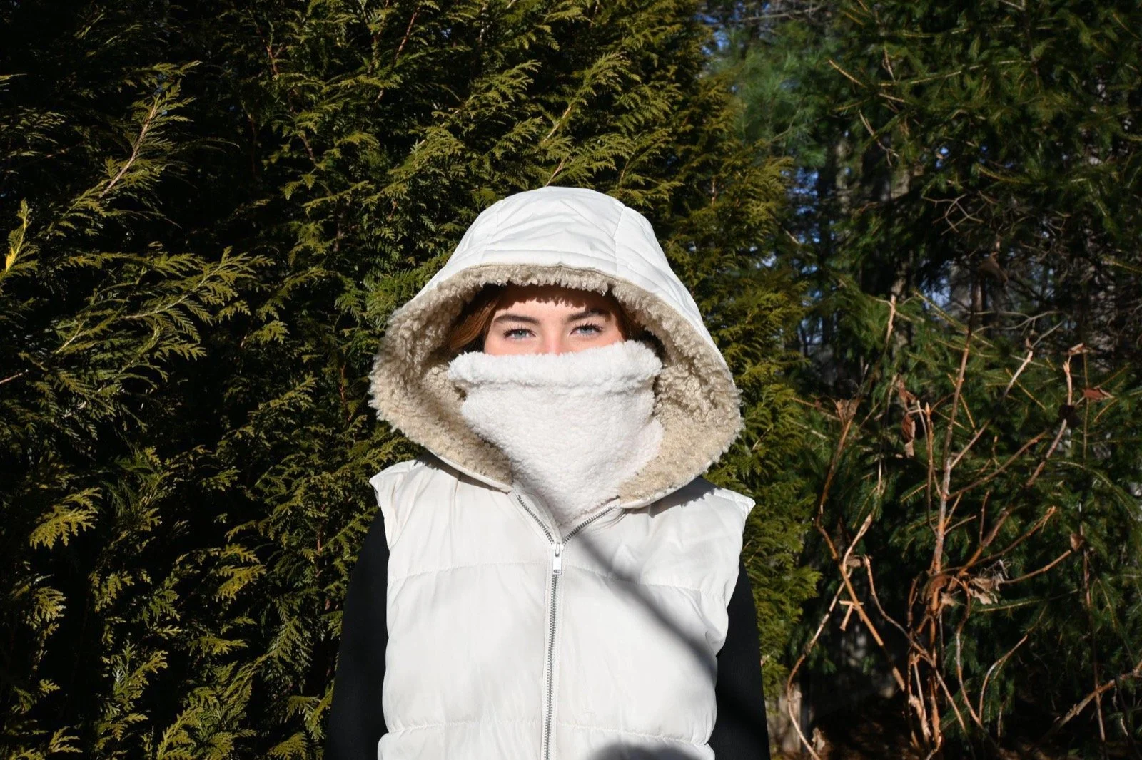 Person in a cream hooded vest wearing the Cream Sherpa neckie pulled up over their mouth