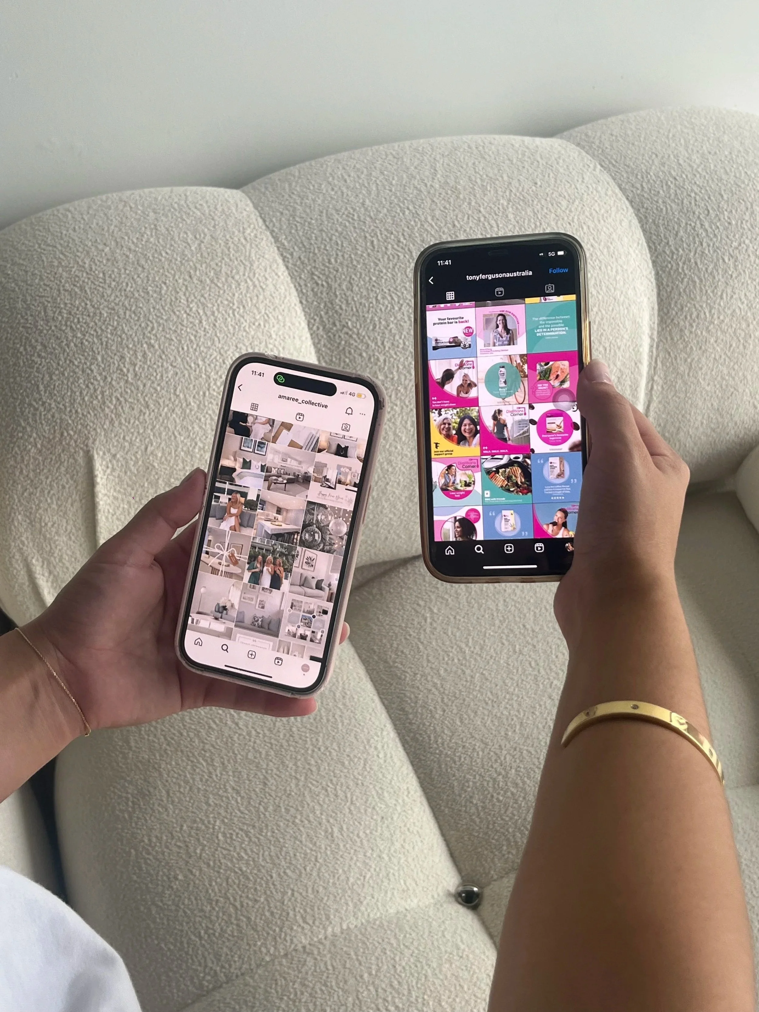 Two hands holding smartphones with social media app feeds over a white textured armchair.
