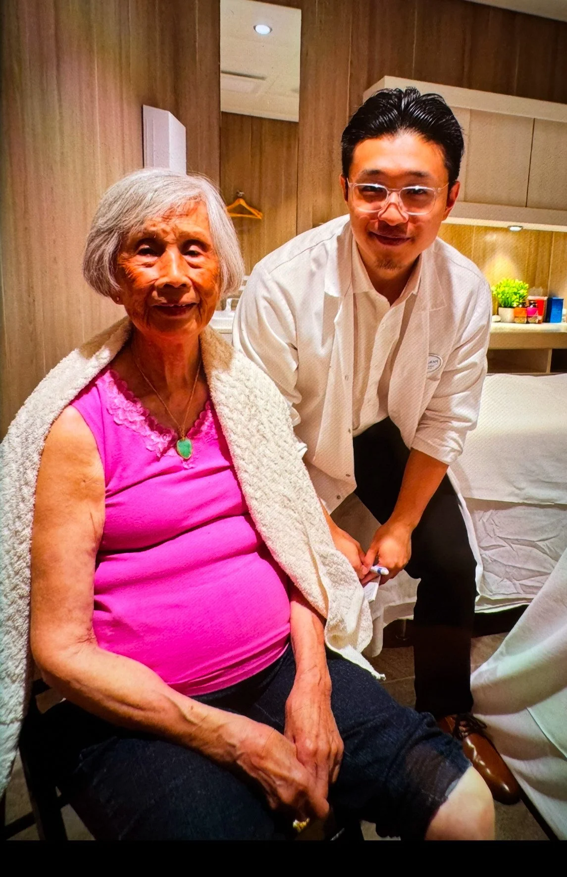 Elderly woman sitting with a young man in a warmly lit modern room, representing a patient’s relief from shoulder pain after acupuncture treatment with The Gentle Needle Guy in Brisbane.