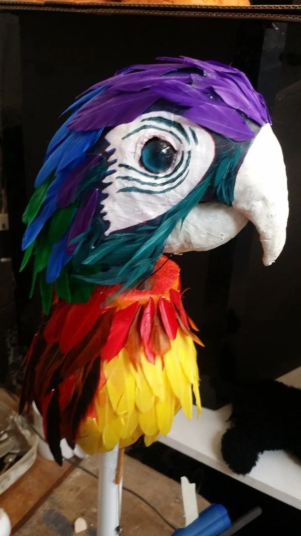 A colorful parrot mask with feathers and a large beak.