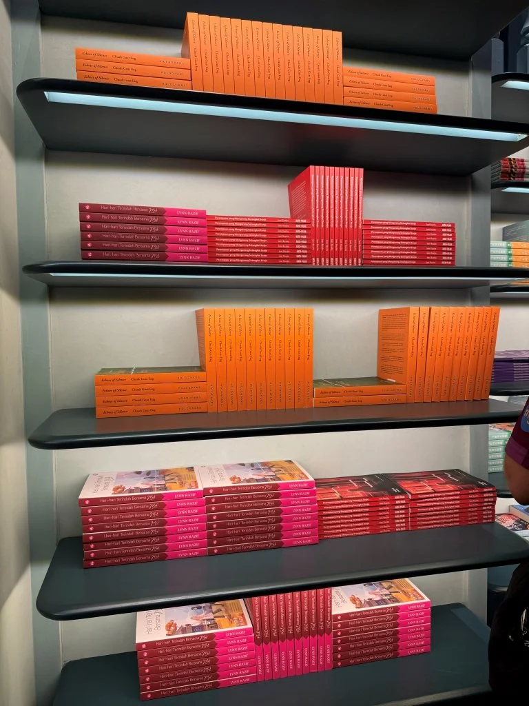 Red and orange-spined book covers displayed on a shelf at Aesop Women's Library 2026