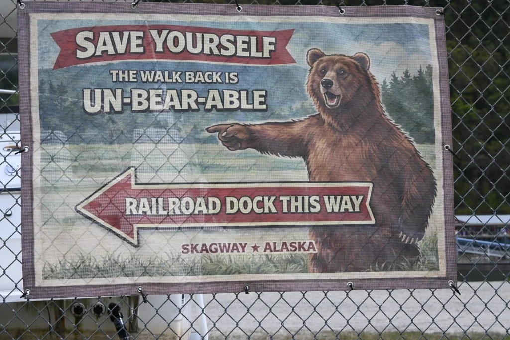 Humorous bear directional sign pointing to Railroad Dock in Skagway Alaska reading Save Yourself the Walk Back is Un-bear-able