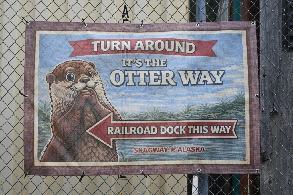 Humorous otter directional sign pointing to Railroad Dock in Skagway Alaska reading Turn Around It's the Otter Way