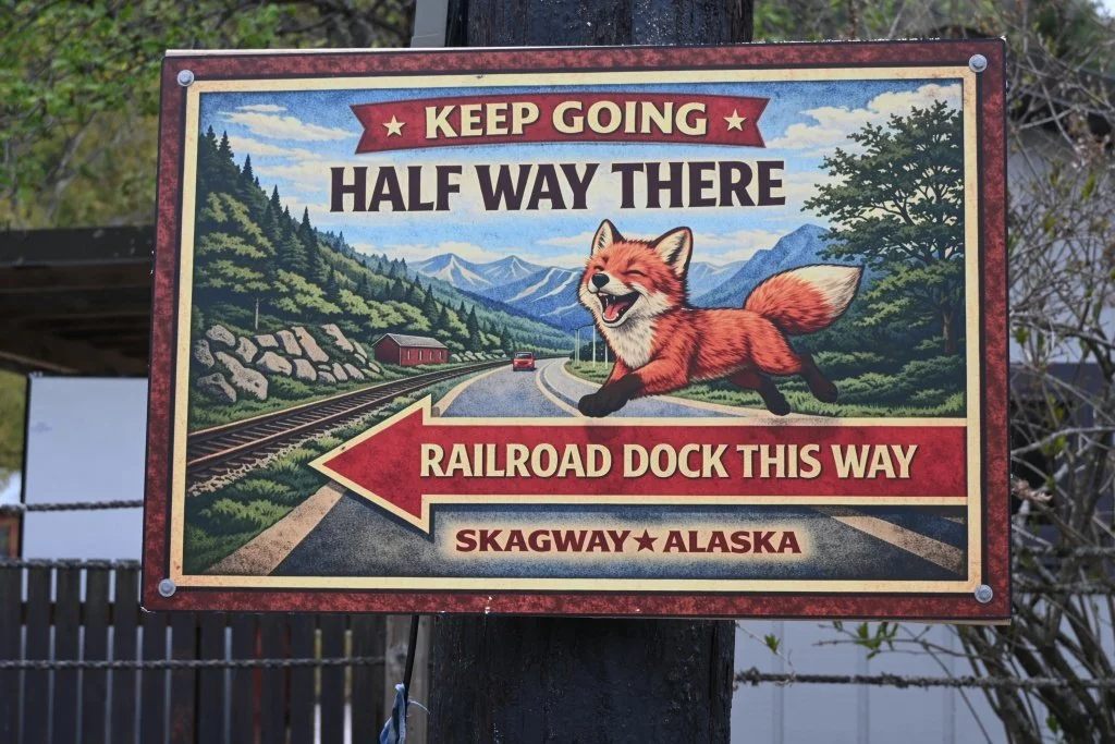 Humorous fox directional sign pointing to Railroad Dock in Skagway Alaska reading Keep Going Halfway There