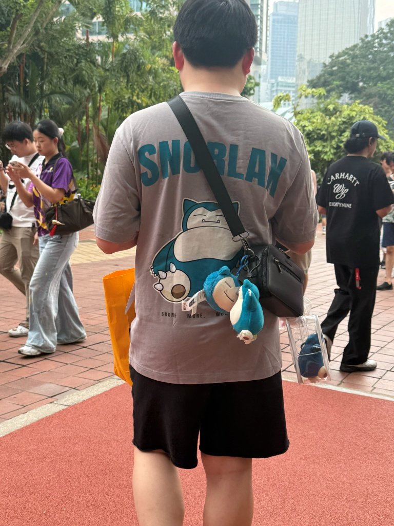 A fan wearing a Snorlax-print t-shirt with a matching Snorlax plush keychain on his bag strap at PokéXciting! Kuala Lumpur