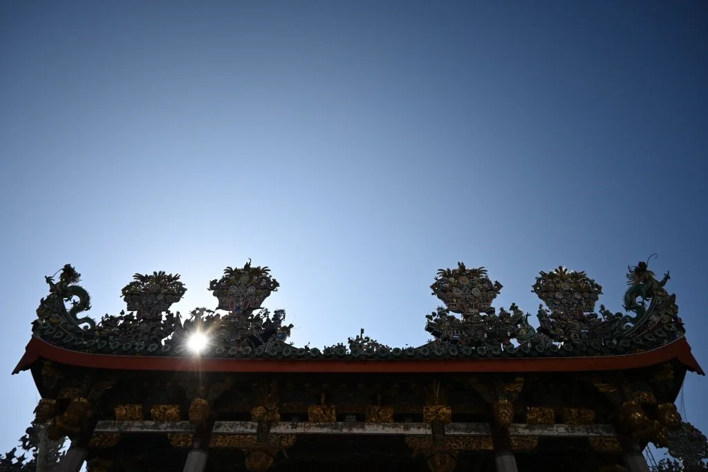 Sunstar breaking through the ornate roofline of Khoo Kongsi clan temple, Penang, Malaysia