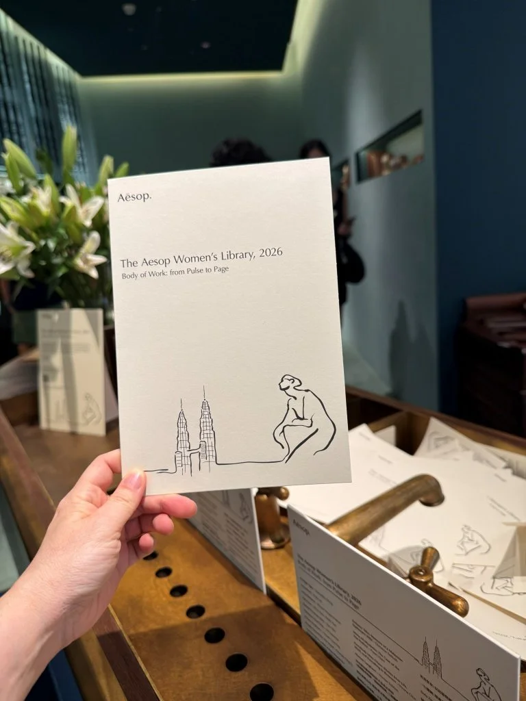 A hand holding an Aesop Women's Library 2026 information card
