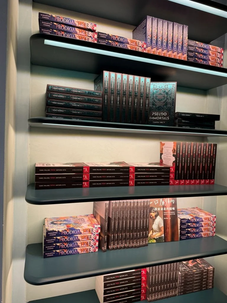 Black and dark-spined book covers displayed on a shelf at Aesop Women's Library 2026