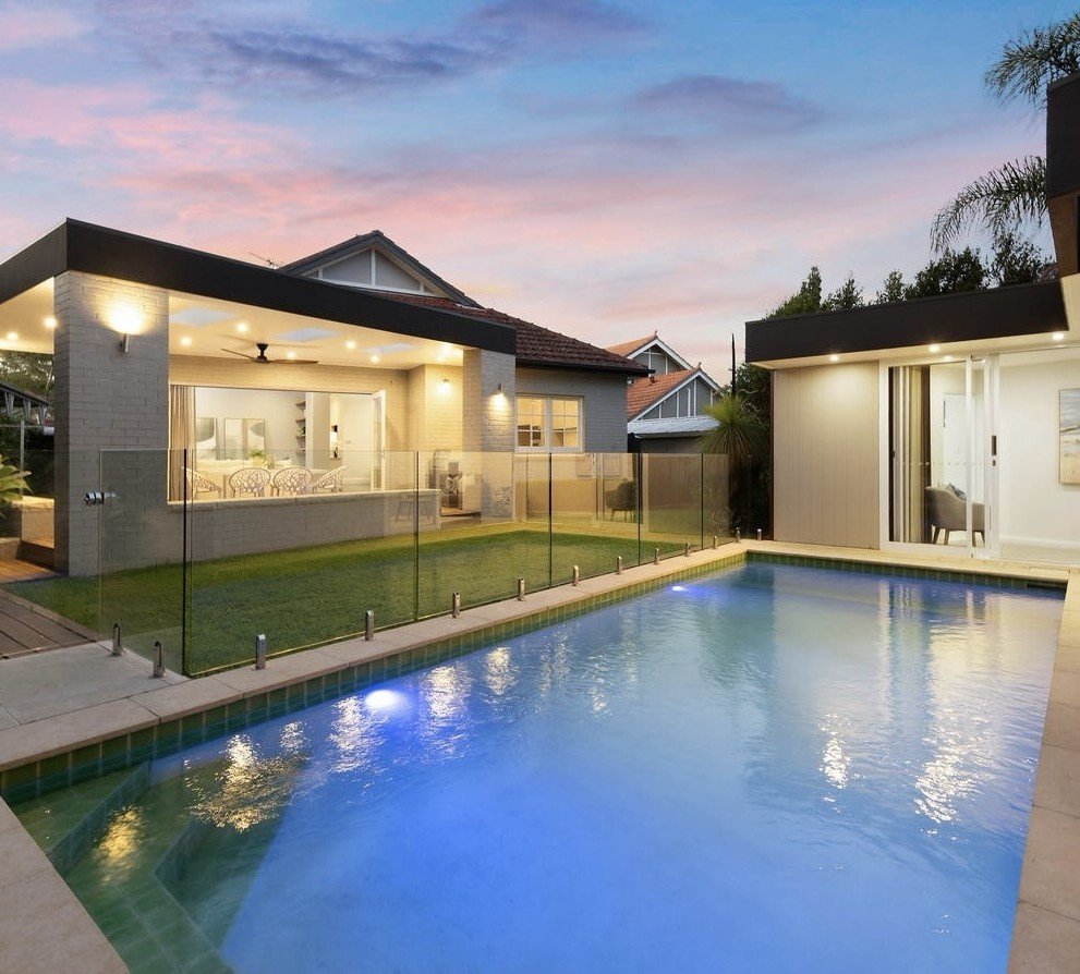 Contemporary pavilion and swimming pool lit at twilight, with the original tiled gable of the bungalow behind, Roseville