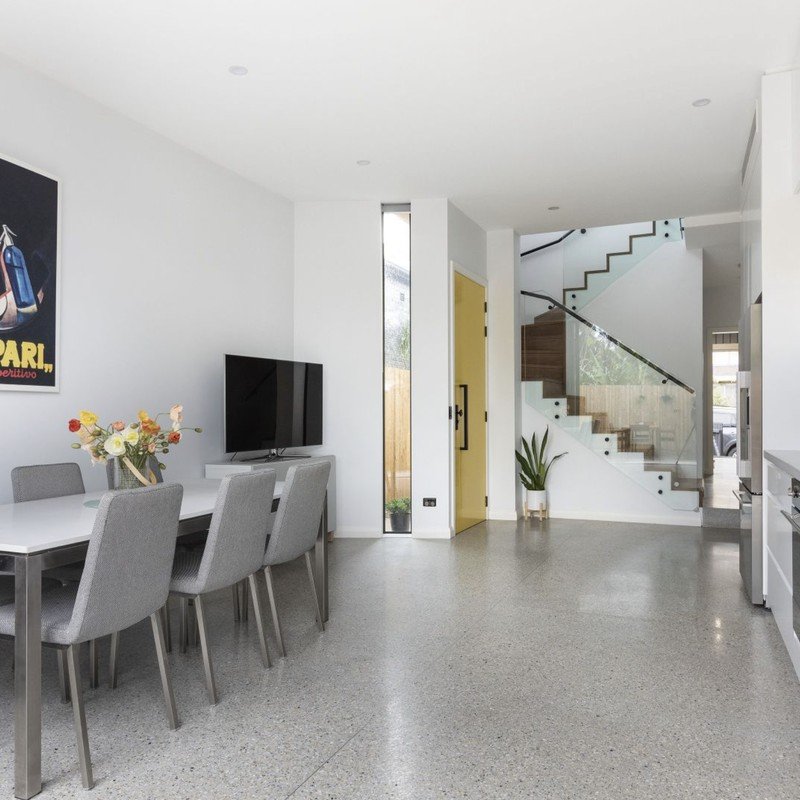 Open-plan dining and living on polished concrete, looking through to the stairwell of a first-floor addition, Lewisham