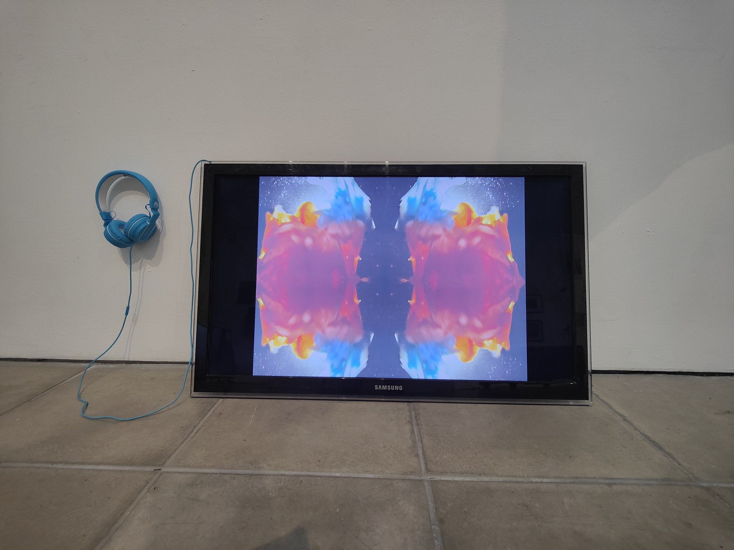 Installation View | The Flesh | Surreal colour fields projected on TV monitor with headphones. A dreamlike visual from The Flesh displayed on a TV monitor leaning against the wall. Headphones accompany the setup for an intimate multisensory experienc