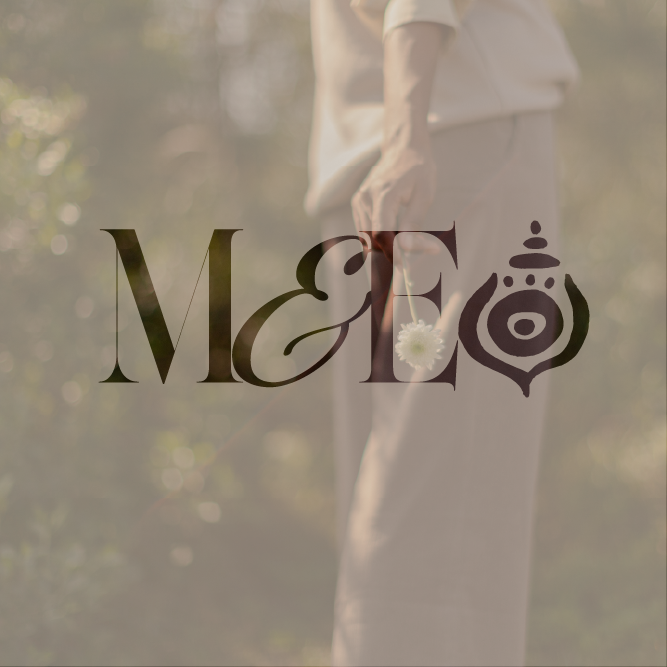 Moss & Ember monogram logo in dark brown overlaid on a soft-focus photograph of a person holding a flower in a garden setting