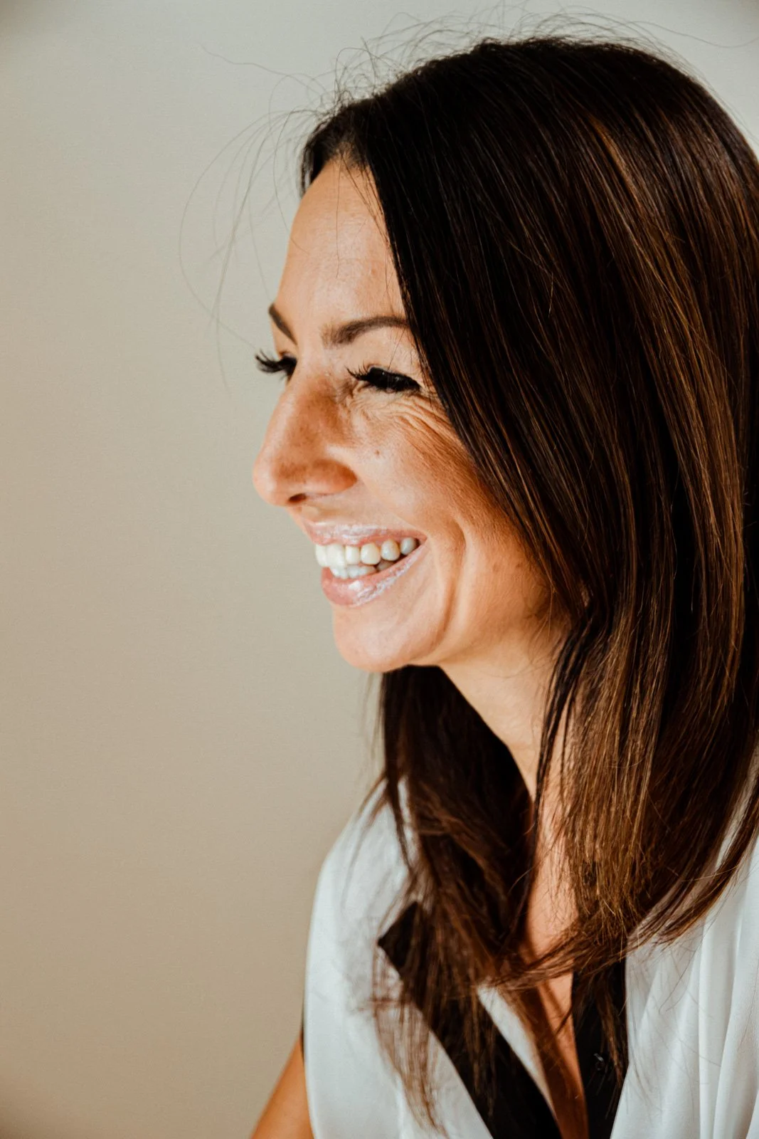 Woman laughing in profile during a personal branding photoshoot, soft natural light — photography by Wild Mind Studios