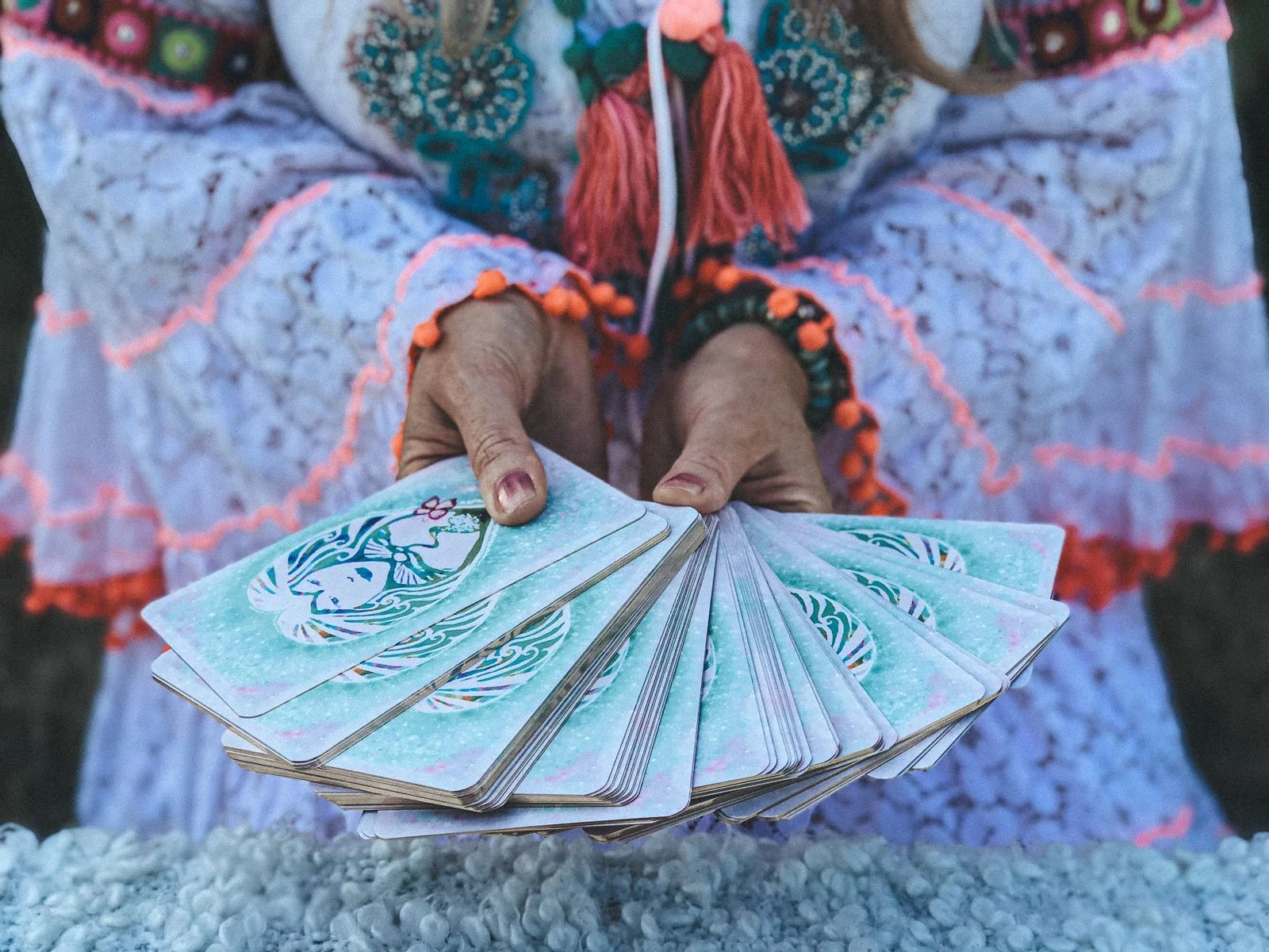 Hands fanning out illustrated oracle cards, detail shot from a bohemian personal branding photoshoot for Emma Penman by Wild Mind Studios