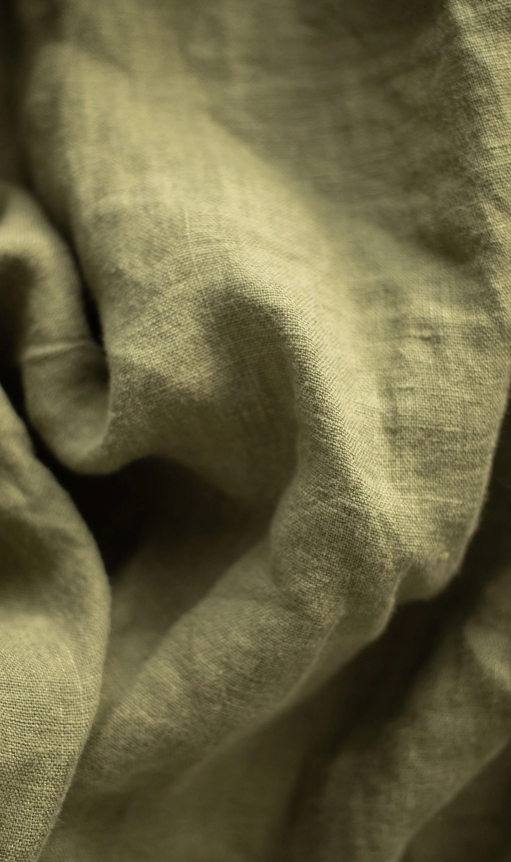 Close-up of draped olive linen fabric with soft folds and texture — mood image representing brand identity design by Wild Mind Studios