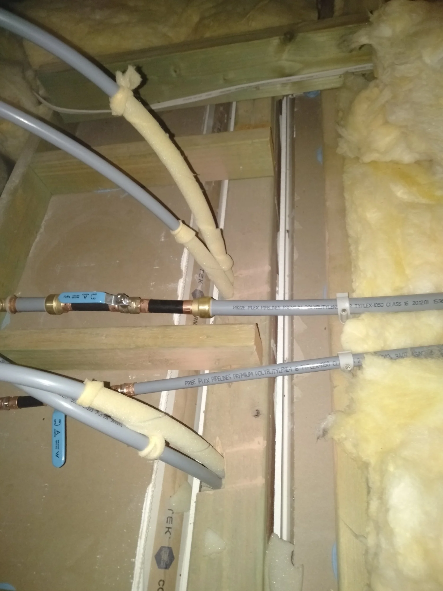 Plumbing pipes and foam insulation in a building under construction.