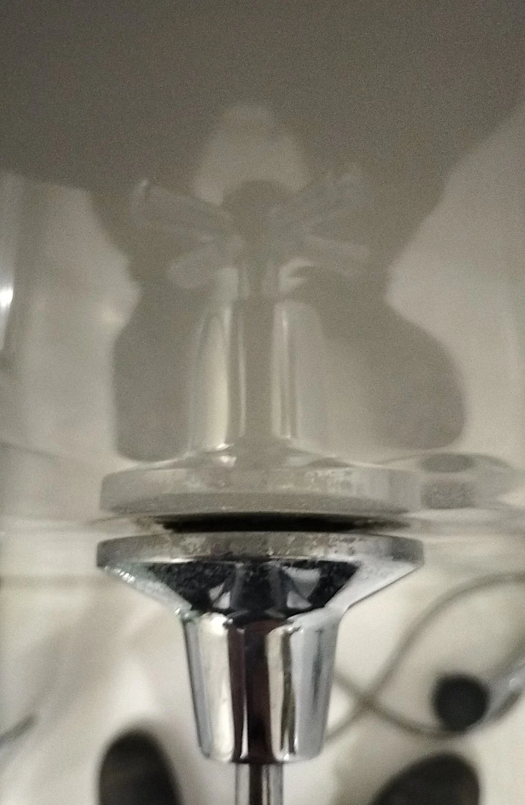 Close-up of a metallic kitchen sink drain with a black rubber gasket or washer.