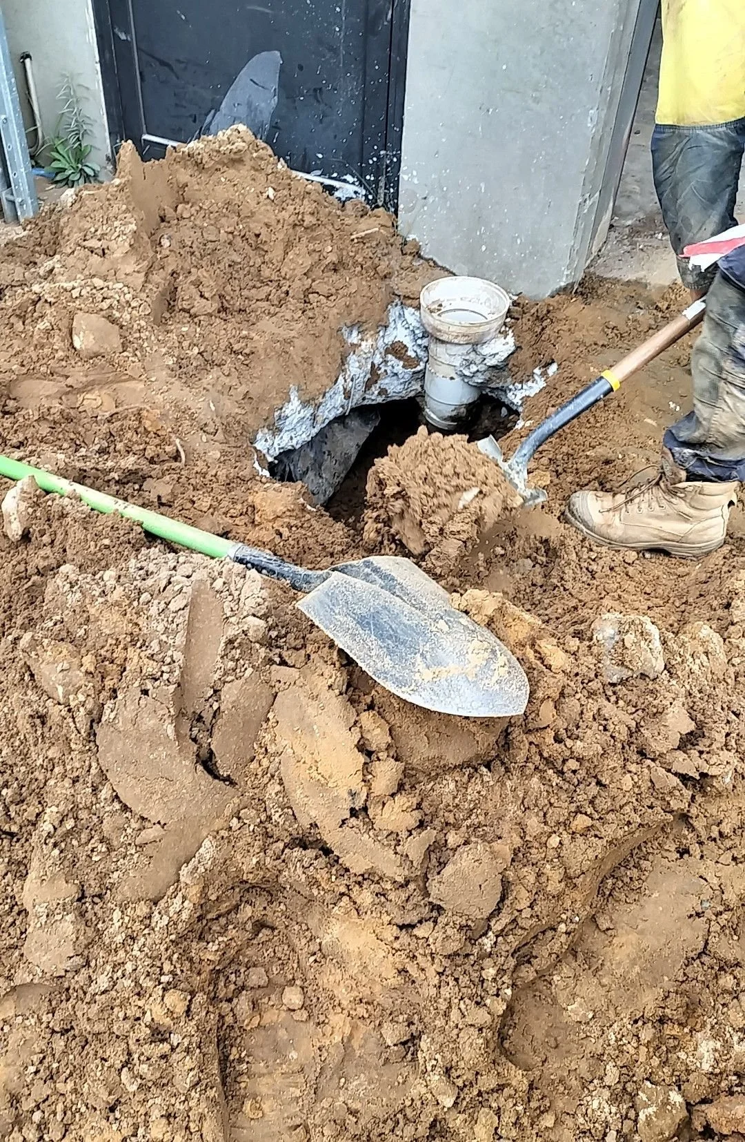 Workers digging a hole in the ground for underground plumbing installation.