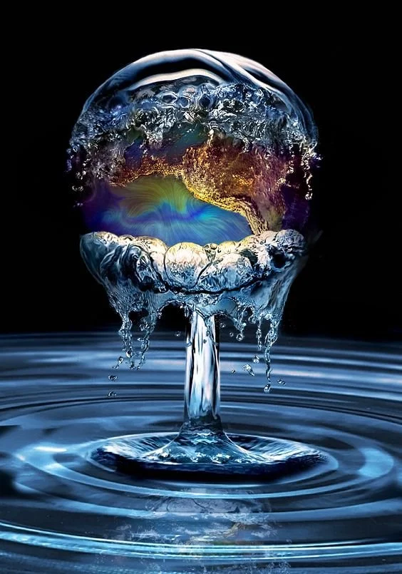 A water droplet splashing and forming a sphere with colorful reflections inside, creating a crown-like shape at the bottom, with ripples on the water surface below.