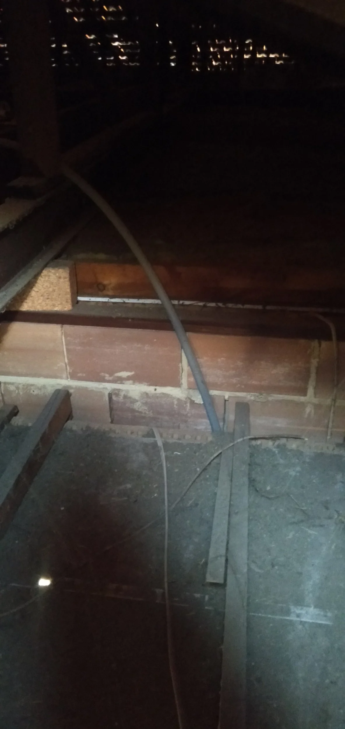 Nighttime attic view with exposed brick wall and visible electrical wiring.