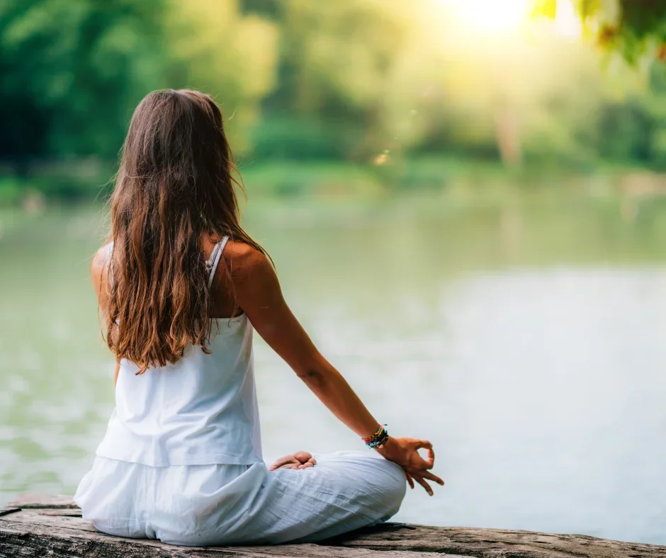 Meditation in der Natur – Frau sitzt am See, Symbol für den Grundlagenkurs Meditation in der Schweiz