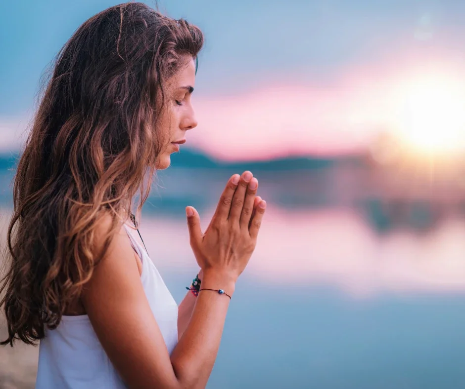 Basisausbildung Energetisches Heilen – junge Frau mit gefalteten Händen in Gebetshaltung, Symbol für Konzentration, Frieden und Heilung