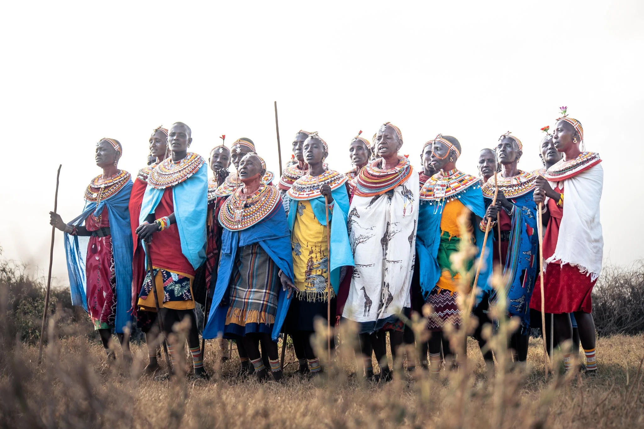 Group of Samburu men wearing traditional beaded jewelry, holding spears, standing outdoors during sunset. This is taken in Northern Kenya with Enkare Wild