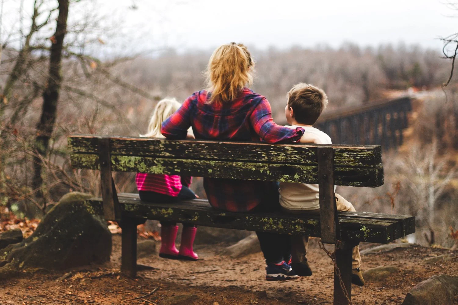 Woman thinking on bench with her two children