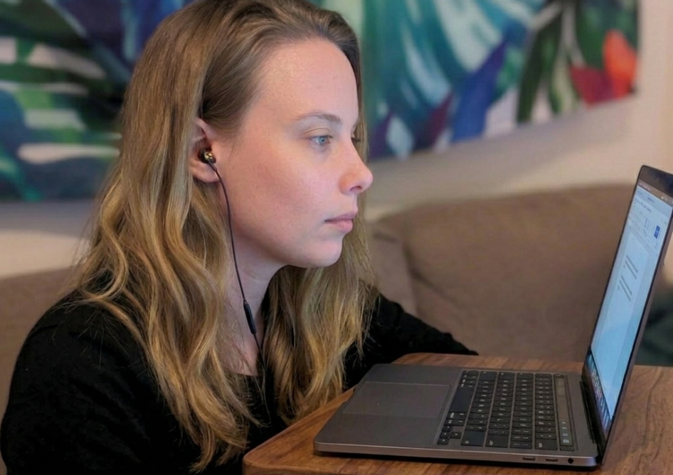 Hannah O'neill sat at laptop with tropical background