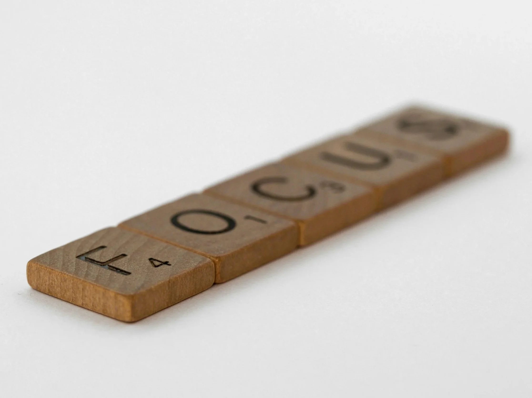 Wooden Scrabble tiles spelling out LET, 4, O, C, G, D on a white background.