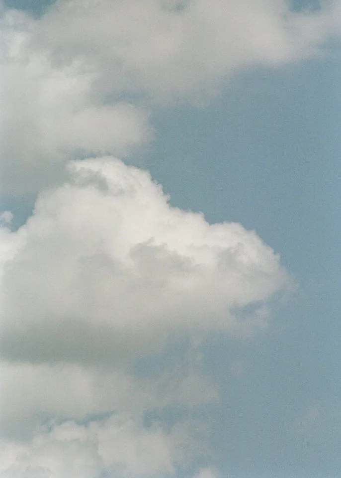 Analog film photograph of white clouds against a blue sky.