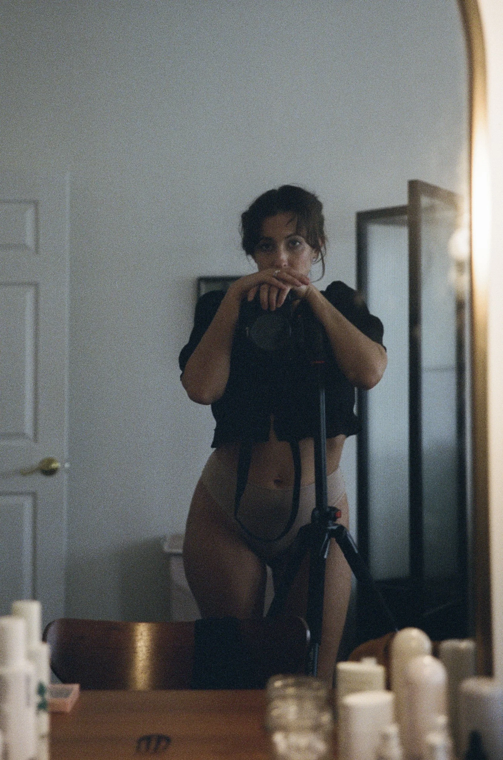 Dark, atmospheric analog self-portrait by Emily Zoe, using shadow and available light to obscure portions of the figure.