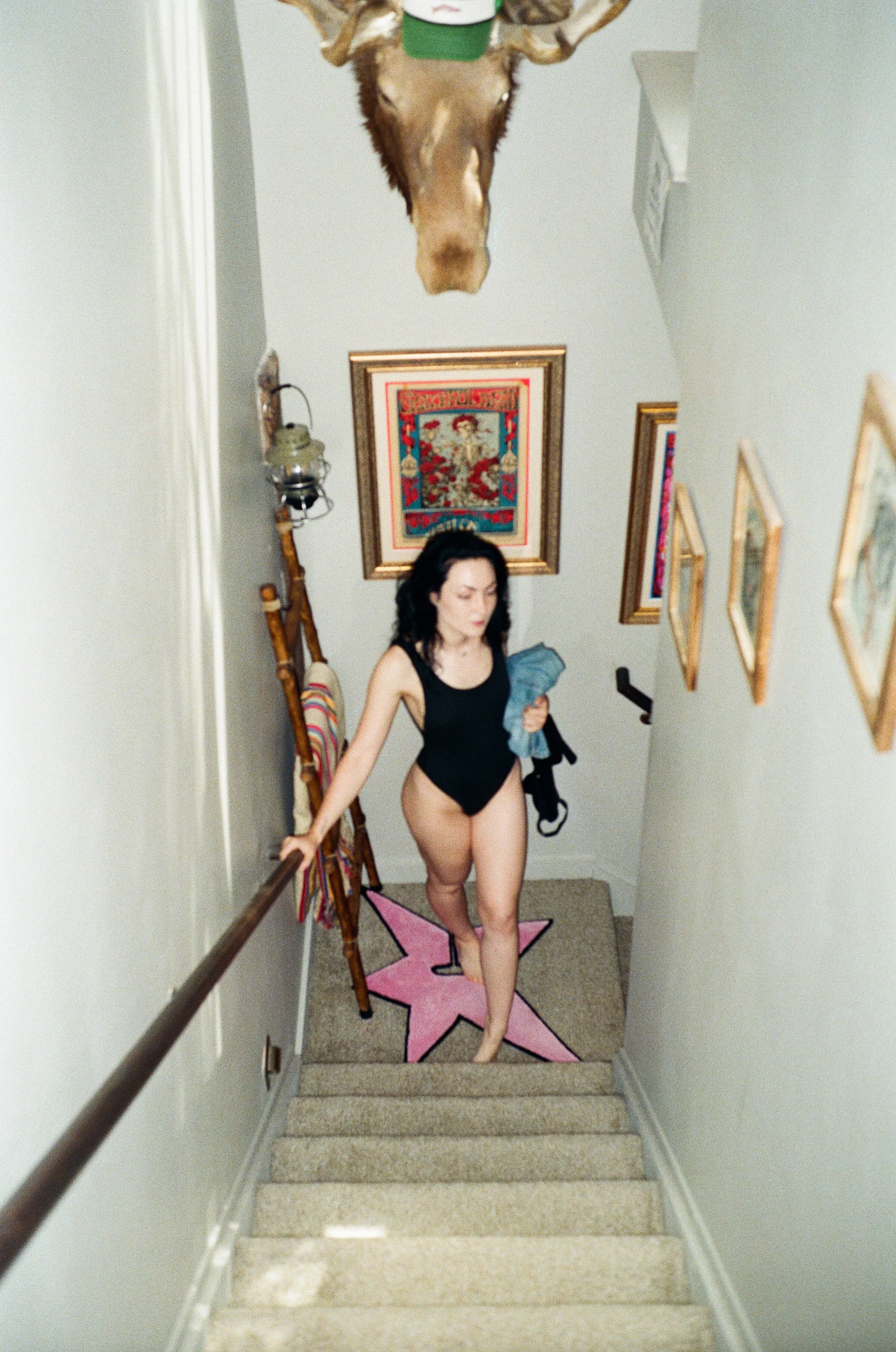 Analog film photograph of a woman within a stark interior stairwell, using architecture, negative space, and figure by Emily Zoe.