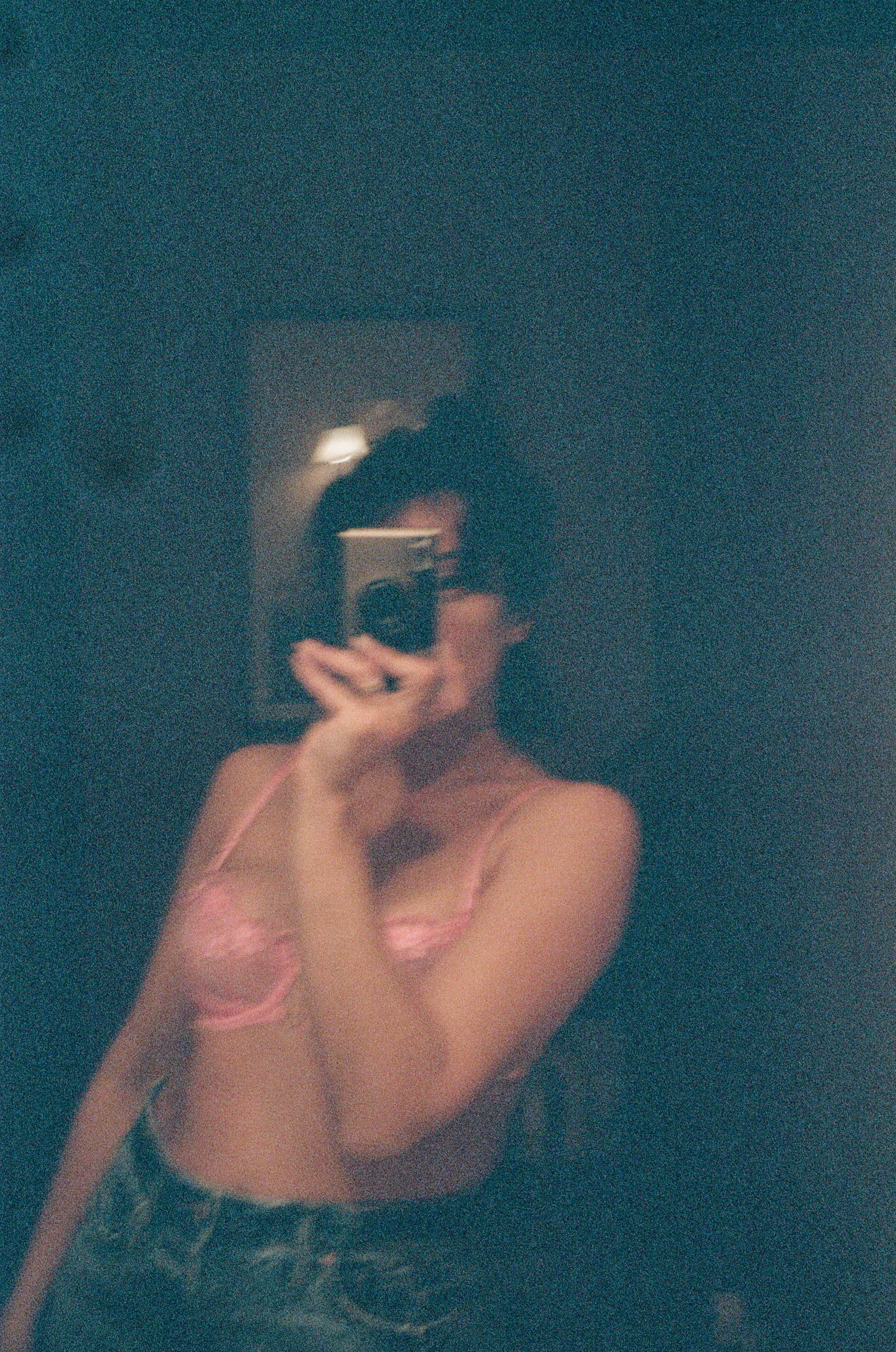 Shadowed analog self-portrait by Emily Zoe, with the figure emerging from a dark interior.