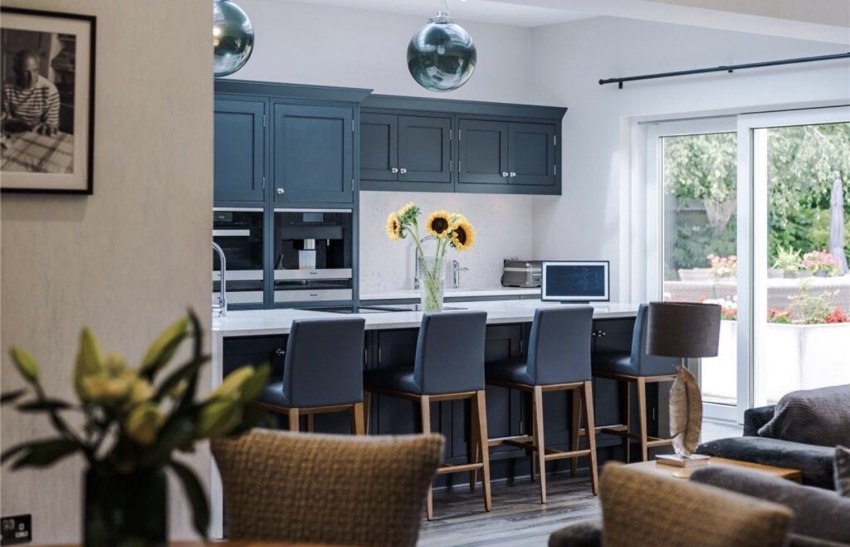Regent Avenue, Lytham St Annes — Kitchen and Family Living Interior — contemporary open-plan kitchen and family room featuring bespoke blue cabinetry, a generous breakfast island with upholstered seating, pendant lighting and garden-facing glazing. T
