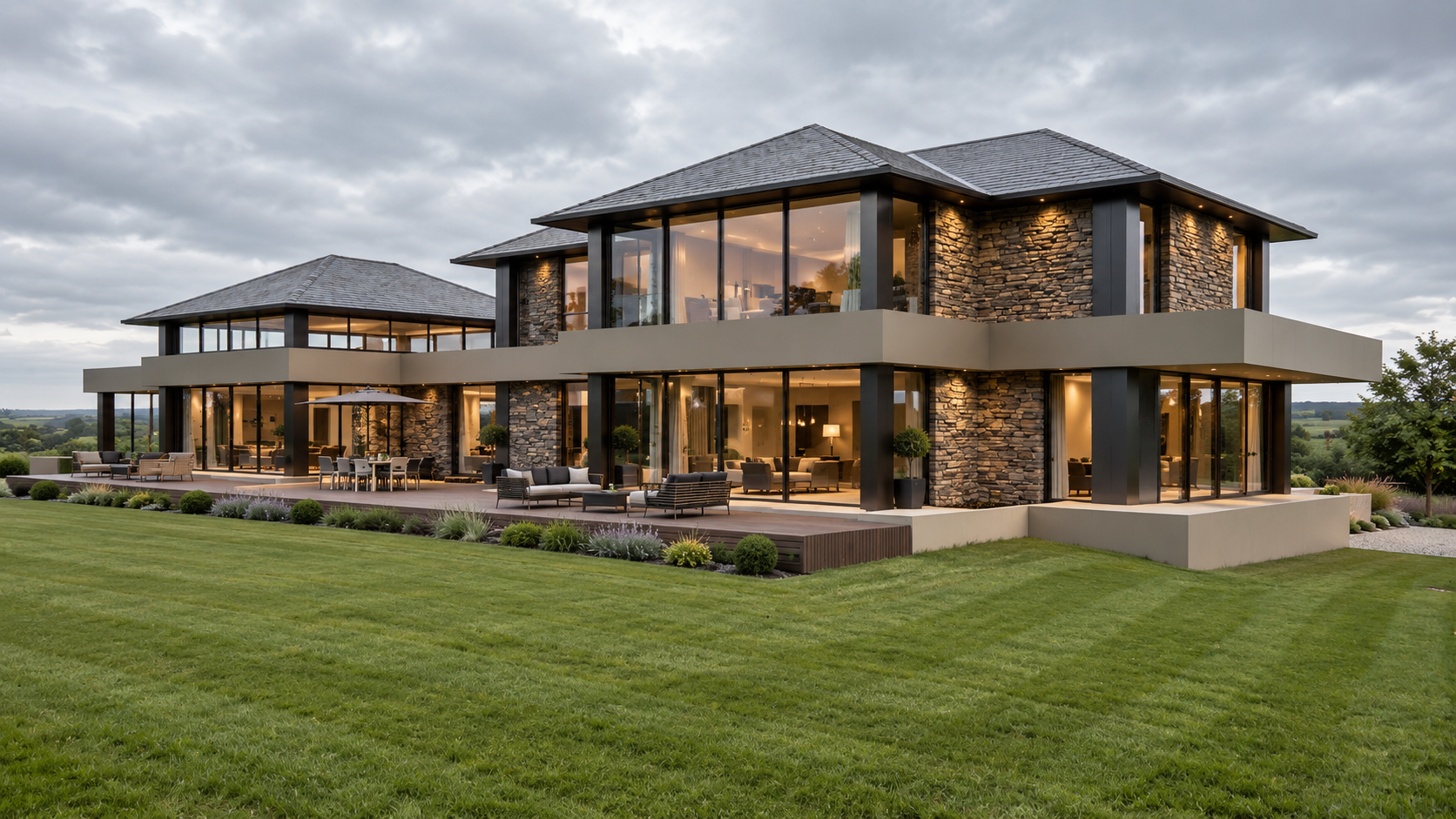 Garden and river-facing elevation of Bankfield, Poolfoot Lane, Singleton, Lancashire, a bespoke new-build country house designed by Chartered Architect Joel Firth. Extensive floor-to-ceiling glazing, natural stone and broad horizontal rooflines open 