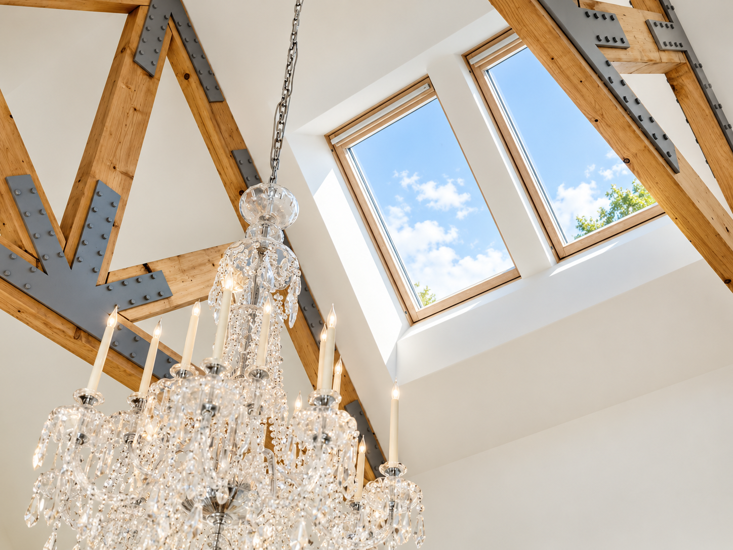 Exposed timber roof trusses and crystal chandelier beneath natural rooflights.