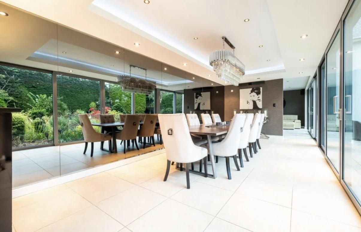 Contemporary dining and entertaining space at Meadowlands, Islay Road, Lytham St Annes, forming part of the major extension and complete refurbishment designed by Chartered Architect Joel Firth. Full-height glazing opens the interior to the garden, b