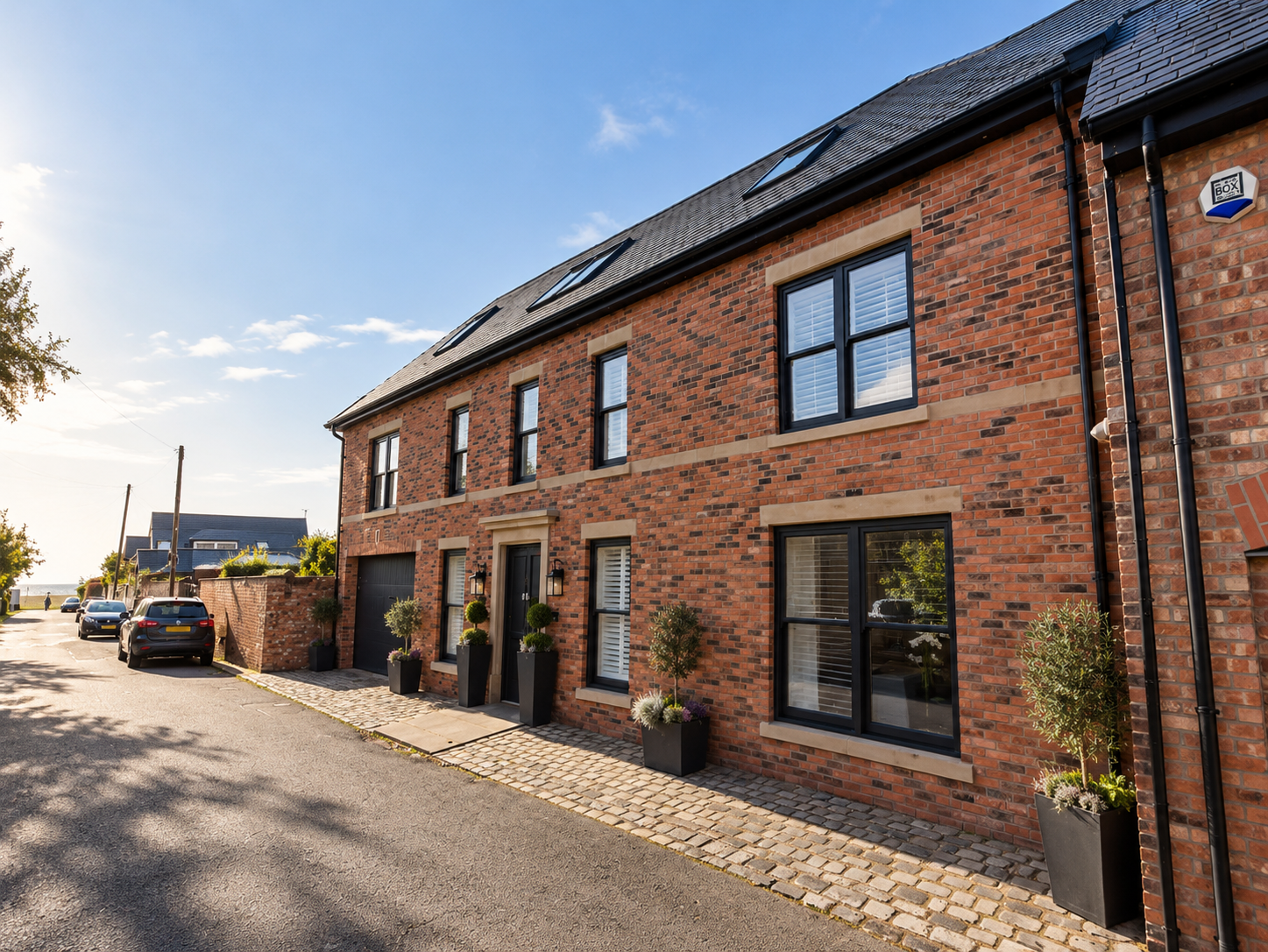 Swainson Street Elevation — Traditional red-brick frontage featuring stone window surrounds, contemporary black joinery, integrated garage and carefully detailed entrance.