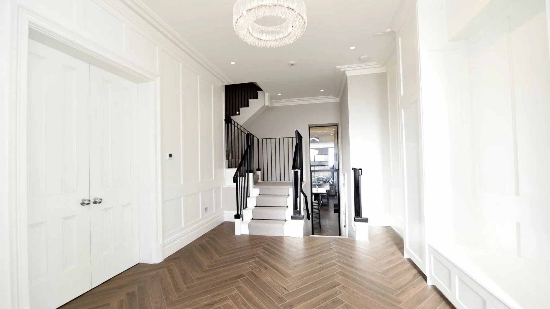 22A East Beach, Lytham — elegant entrance hallway featuring traditional architectural detailing, herringbone timber flooring, statement ceiling lighting and a refined contemporary interior.