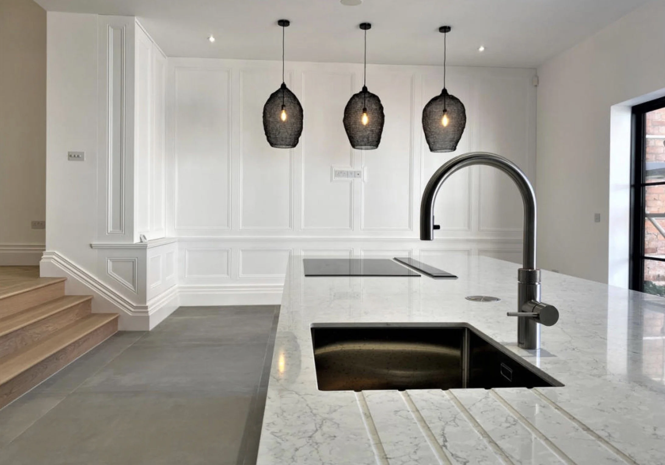 Bespoke kitchen island with marble worktop, black fittings and pendant lighting.