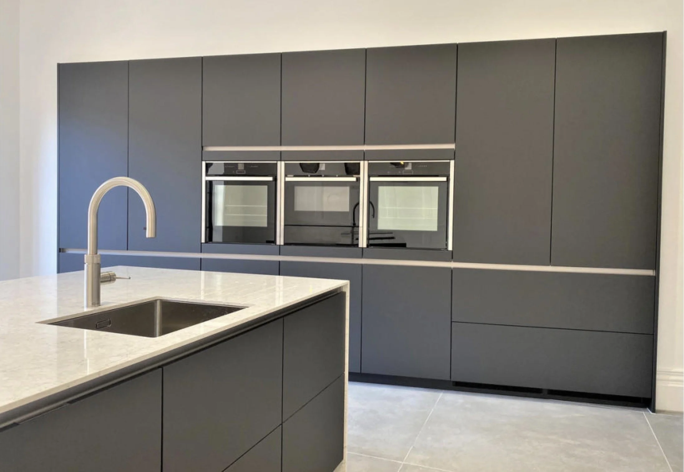 Bespoke kitchen island with marble worktop, black fittings and pendant lighting.