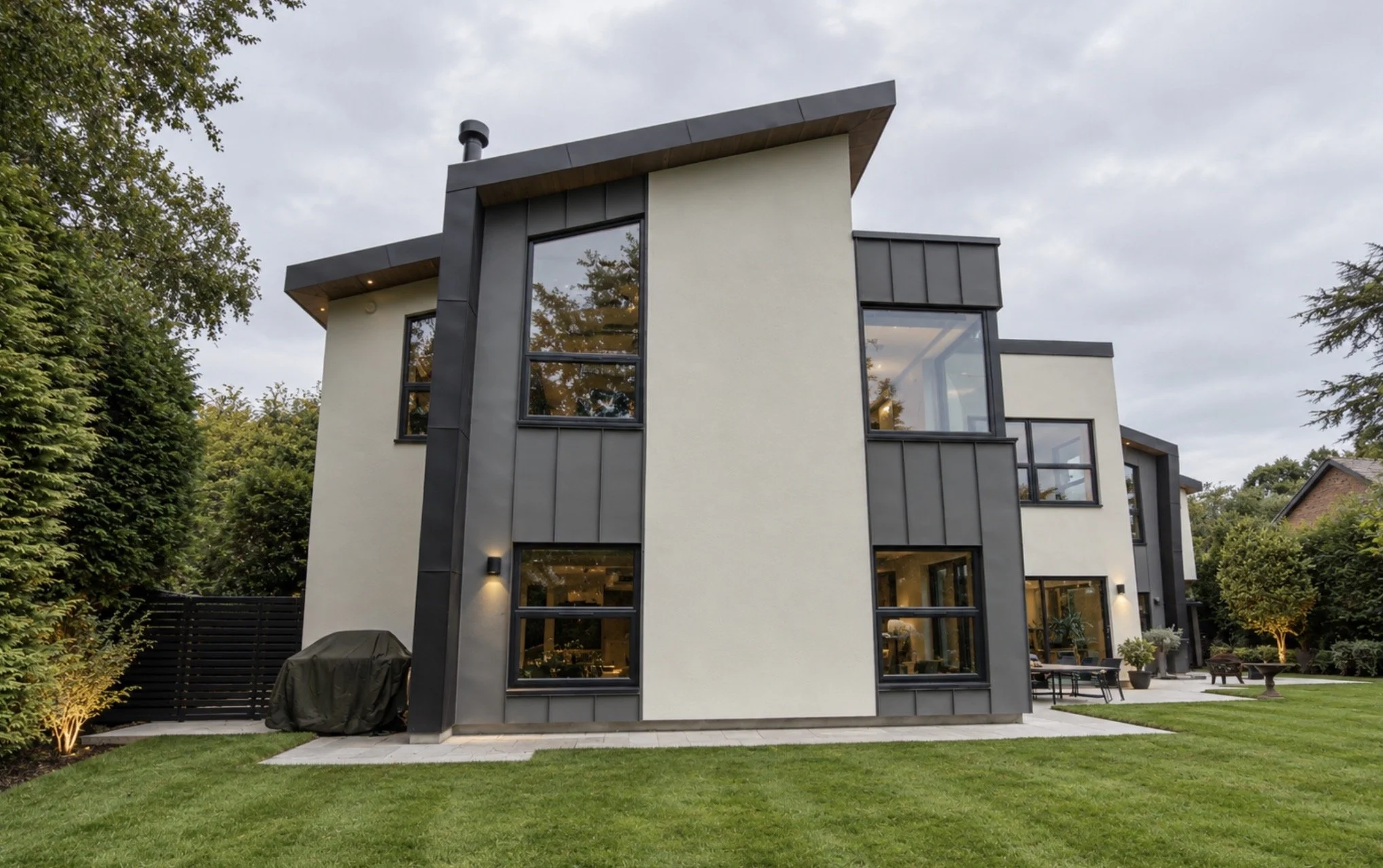     Rear elevation featuring dramatic asymmetric rooflines, full-height glazing and contrasting white render with dark architectural cladding.