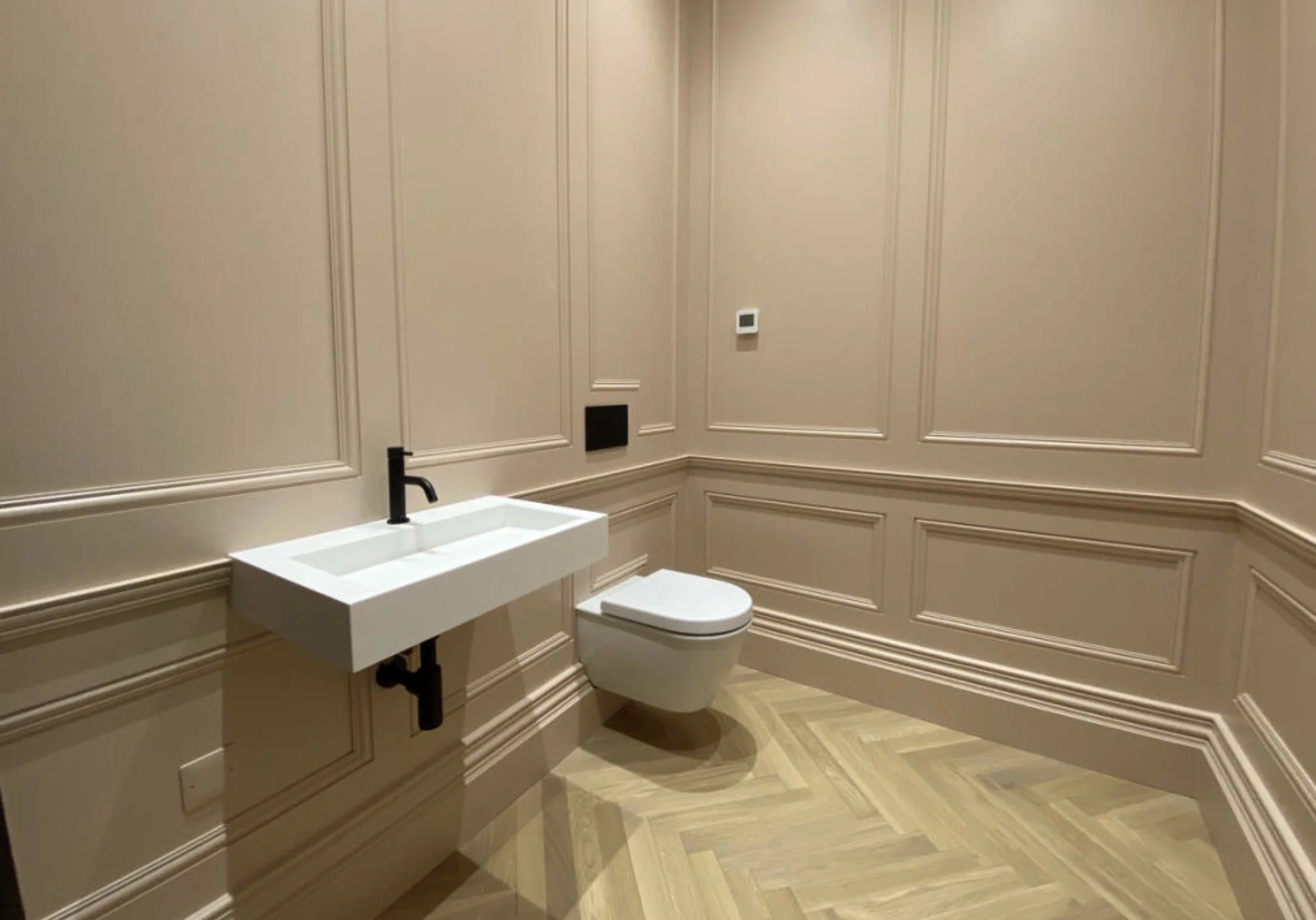 Contemporary cloakroom with wall panelling, natural stone flooring and modern fittings.